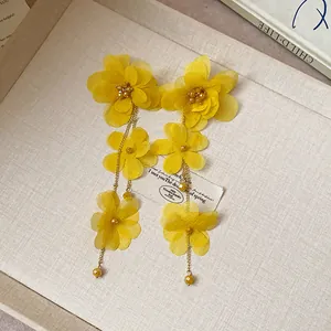 Close-up of yellow chiffon flower tassel earrings featuring delicate gold chains
