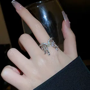 Gros plan d'une bague ouverte en argent avec cristaux marquise suspendus au doigt