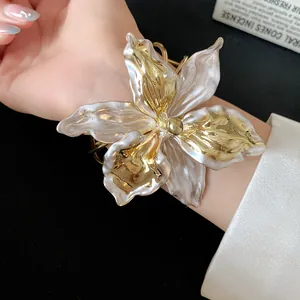 Detailed view of an elegant vintage gold and pearl lily flower open cuff bracelet on a wrist