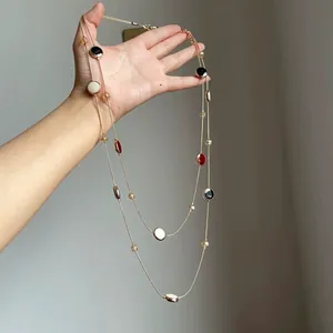 Detailansicht einer zweireihigen goldenen Halskette mit bunten runden Glasperlen.