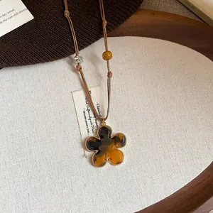 Close-up detail of a retro flower pendant necklace featuring tortoiseshell texture