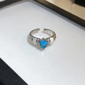 Vue détaillée d'une bague argentée ouverte avec pierre bleue ovale et accents blancs