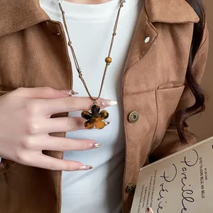 Detailed view of flower pendant necklace in Maillard style with brown adjustable cord