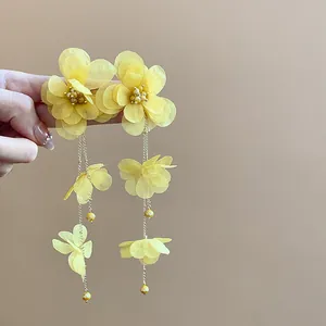 Detail of yellow chiffon flower tassel earrings with golden chain and beads