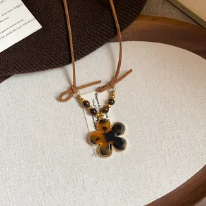Detail view of a Maillard style tiger eye flower necklace with a brown leather cord.
