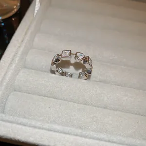 Vue détaillée d'une bague argentée avec pierres cœur et carrées dans un écrin en velours
