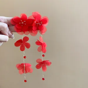 Detailed view of red chiffon flower tassel earrings with golden chains and beads.