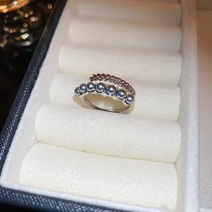 Gros plan d'une bague réglable en argent avec perles grises et motif épis de blé