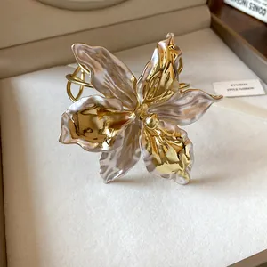Detailed close-up of a luxury gold and pearlescent lily flower open bangle bracelet