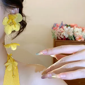 Close-up of vibrant yellow chiffon flower tassel earrings on an Asian model skin