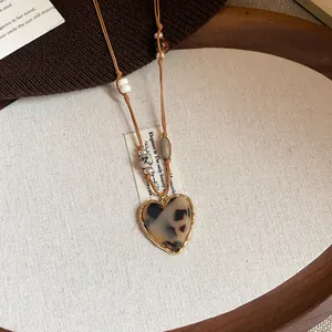Close-up of heart-shaped leopard print necklace with tiger eye stone beads in warm brown tones.