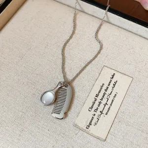 Dettaglio della collana d'argento con ciondoli pettine e specchio su lino