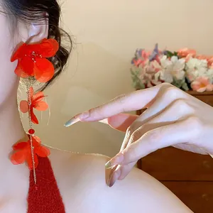 Detail view showing vibrant red chiffon flower tassel earrings with golden chains