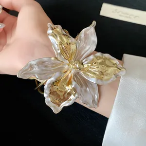 Detailed view of an elegant gold and white resin lily flower open cuff bracelet