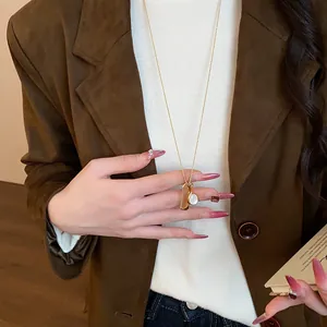 Vista dettagliata di un'elegante collana d'oro con ciondoli a pettine e specchio su blazer
