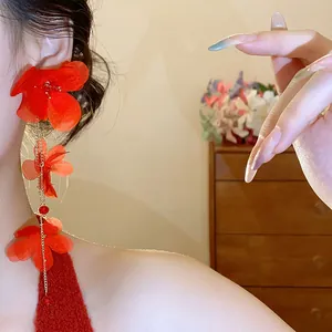 Detail of red chiffon flower tassel earring worn on ear for a vacation look