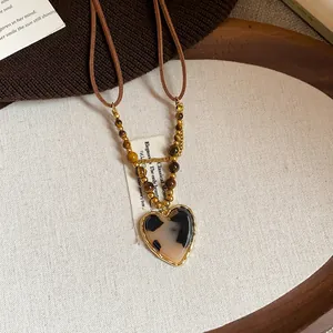 Detailed shot of tiger's eye bead necklace with a heart-shaped leopard print pendant