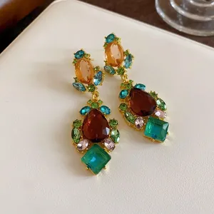 Primer plano de pendientes colgantes vintage con gemas multicolores en engaste dorado.
