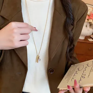 Primo piano di una collana dorata con ciondoli a forma di pettine e specchio su catena