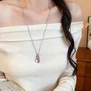 Primo piano di una collana in argento con ciondolo a pettine e specchio indossata da modella.
