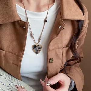 Detailed view of a vintage heart pendant necklace with leopard print on a brown cord.