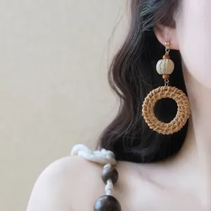 Nahaufnahme von runden Rattan-Ohrringen im Bohème-Stil an einem asiatischen Modellohr