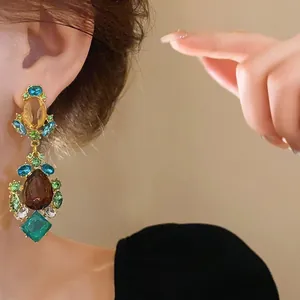 Primer plano de pendientes largos de gemas coloridas para un estilo vintage elegante.