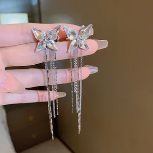 Close-up of silver butterfly ear clips with crystal wings and long tassel chains