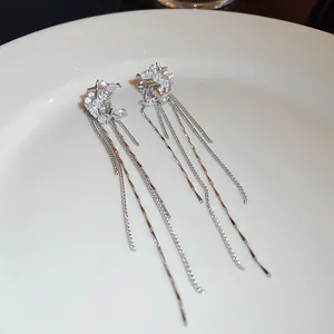 Detailed view of silver triple-layered tassel earrings with shimmering stone clusters.