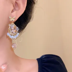 Gros plan détaillé de boucles d'oreilles élégantes en cristal à pompons et papillons