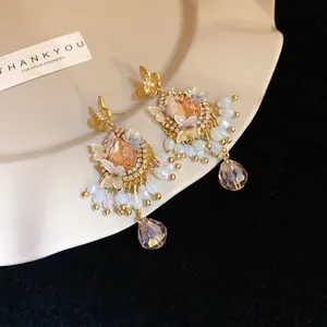 Détail de boucles d'oreilles papillon vintage avec gemmes pêche et franges de cristal