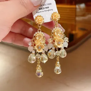 Detail view of floral chandelier earrings with crystals and peach roses