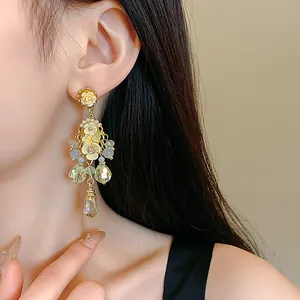 Close-up detail of a floral crystal tassel drop earring with pearl accents on a model.
