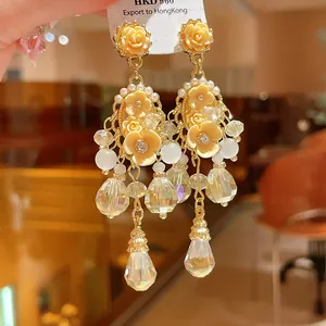High-detail macro shot of elegant champagne flower earrings with crystal tassel drops