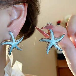 Close-up detail of light blue enamel starfish stud earrings with elegant silver edges