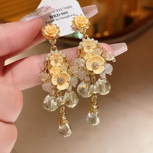 Detailed close-up of champagne flower earrings with dangling crystals and pearls