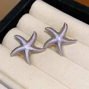 Close-up view of elegant lavender enamel starfish stud earrings in a velvet jewelry box