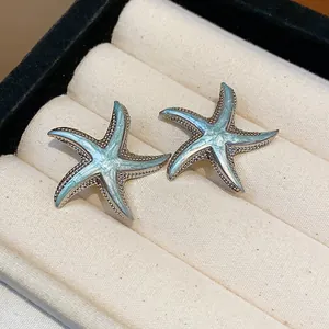 Close-up detail showing the glossy blue enamel texture and silver beading on starfish studs