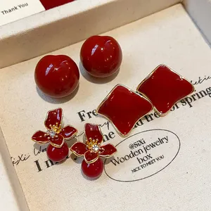 Detailed view of elegant dark red resin earrings in various shapes on a jewelry box