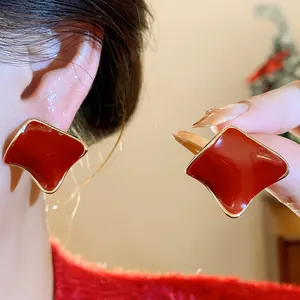 Macro view of elegant Ancora red resin stud earrings with gold metallic trim and silver needles