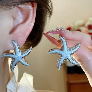 Detailed view of blue starfish stud earrings worn on ear for coastal vacation style.
