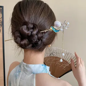 Dettaglio di un fermaglio per capelli con stella marina e perle in uno chignon classico