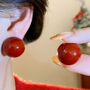 Macro view of deep red resin sphere stud earrings showing smooth and glossy texture