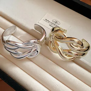 Elegant wide cuff bracelets with twisted knot design in gold and silver finishes.