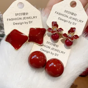Close-up of red resin stud earrings set including flower and geometric shapes