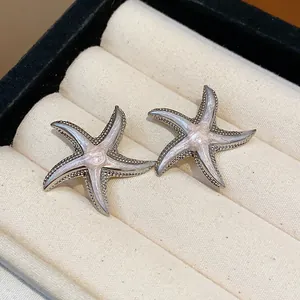 Detailed view of silver-toned starfish stud earrings with pink enamel inlay