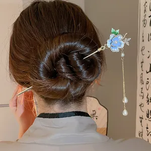 Dettaglio di un elegante fermaglio per capelli a fiore blu con farfalla e perle pendenti