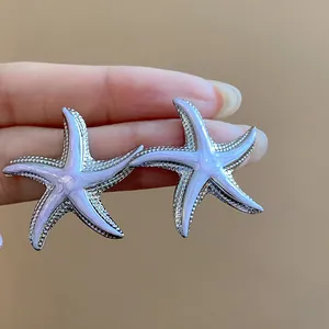 Detail shot of starfish stud earrings featuring lavender enamel and textured silver edges