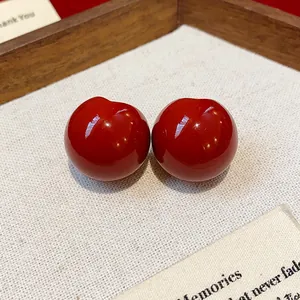 Close-up of gloss red resin stud earrings on a minimalist linen display