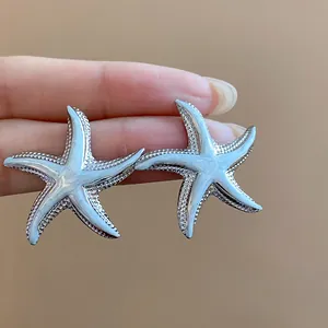 Detailed macro view of silver-tone starfish stud earrings with elegant white enamel finish